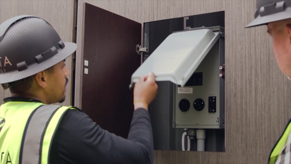 A technician opening an electrical service panel on a REV